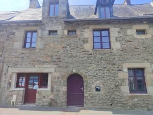 an old stone building with a purple door and windows at Appart Halo et Duplex Les Filles in Dinan