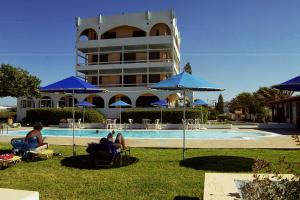 people sitting in lawn chairs near a swimming pool with umbrellas at Hotel Tsagarakis Beach in Amoudara Herakliou