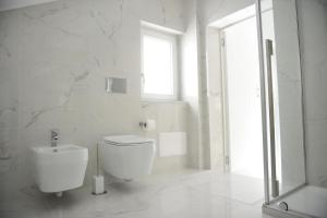 a white bathroom with a toilet and a window at Paradise Luxury Apartment Salerno Center in Salerno