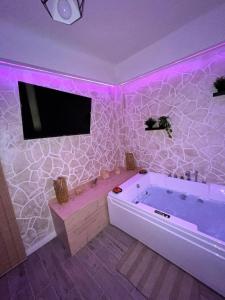 a bathroom with a tub and a tv on the wall at Appartamento con SPA I Due cuori in Taranto