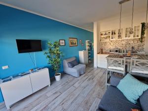 sala de estar con pared azul y cocina en Casa Marina - Monolocale vista mare, en Follonica