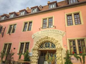 un edificio rosa con un arco delante de él en Hotel Vier Jahreszeiten, en Volkach