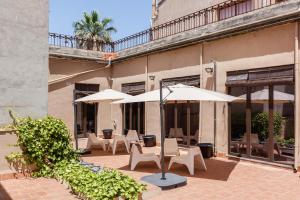 Un patio con mesas, sombrillas y sillas. en Apartament Merlot, en Vilafranca del Penedès