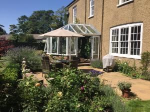 a garden with a greenhouse in front of a house at The Oaks in Swaffham