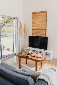 uma sala de estar com uma mesa de centro e uma televisão de ecrã plano em S T U D I O 22 Peaceful Retreat with Garden Views em Port Lincoln