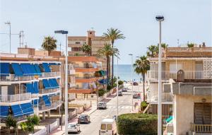 une rue de la ville avec des bâtiments, des palmiers et l'océan dans l'établissement Amazing Apartment In Santa Pola With Wifi, à Santa Pola