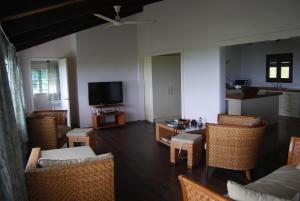 sala de estar con sillas de mimbre y TV en Moana Villa Aitutaki, en Arutanga