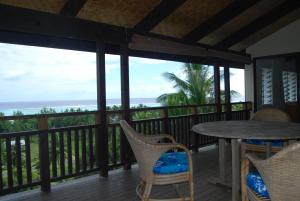 einen Balkon mit einem Tisch, Stühlen und Meerblick in der Unterkunft Moana Villa Aitutaki in Arutanga