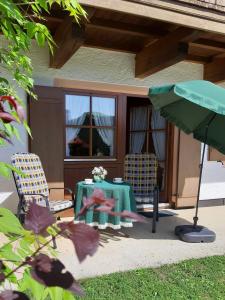 Un patio con dos sillas y una mesa y una sombrilla. en Ferienwohnung Lübbers, en Reit im Winkl