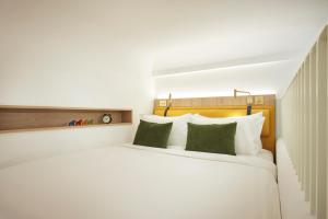 a bedroom with a large white bed with green pillows at Citadines Connect City Centre Singapore in Singapore