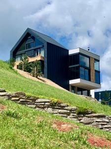 a black house on top of a grassy hill at Panorama Lofts Pec in Pec pod Sněžkou