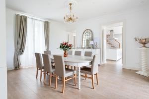 a white dining room with a table and chairs at Domaine Les Jardins dArsene in Tinténiac