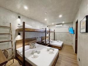 a room with two bunk beds and a table at Shorebreak Hostel San Juan La Union in san juan la union