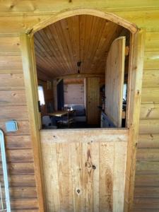 een open deur van een houten hut met een houten wand bij La Maison du Bonheur Roulotte in Saint-Ouen-sous-Bailly