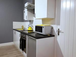 a white kitchen with a microwave and a stove at The Westside with Parking in York