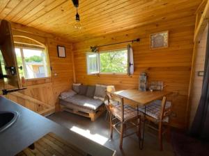 a room with a table and a couch in a cabin at La Maison du Bonheur Roulotte in Saint-Ouen-sous-Bailly