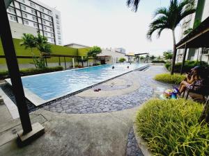a swimming pool with people sitting next to a building at Steff's Condo 815 at CENTRIO Tower Deluxe Unit in Cagayan de Oro