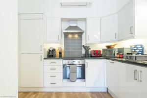 a white kitchen with white cabinets and a stove at Mawnan in Mawnan