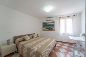 a white bedroom with a bed and a sink at Pepigall Apartments in Alghero