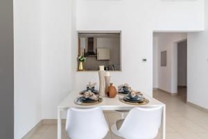 The Smart Concierge - Sandoval Gardens JVC في دبي: طاولة غرفة طعام بيضاء مع كرسيين بيض