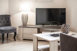 ein Wohnzimmer mit einem TV, einem Stuhl und einem Tisch in der Unterkunft Le Cottage du Louvre in Lens