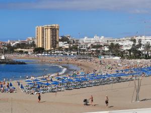 una playa con mucha gente y sillas y el océano en La esquinita, en Los Cristianos