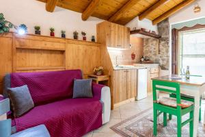 sala de estar con sofá púrpura y cocina en Chalet Altinate Tenna OSPITAR, en Tenna 