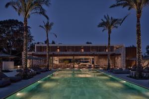 - une piscine bordée de palmiers en face d'une maison dans l'établissement Theros All Suite Hotel - Adults Only, à Kos