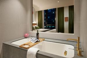 a bathroom with a tub and a large mirror at Citadines Connect City Centre Singapore in Singapore