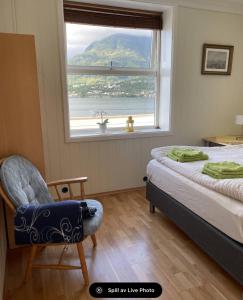 ein Schlafzimmer mit einem Bett, einem Fenster und einem Stuhl in der Unterkunft Fjord Apartments in Dimmelsvik