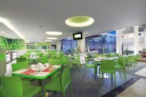 スミニャックにあるファヴホテル サンセット スミニャックの緑の椅子とテーブルのあるカフェテリア