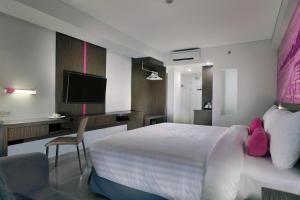 a hotel room with a bed and a television at favehotel Sunset Seminyak in Seminyak