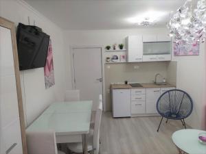 a small white kitchen with a table and a chair at City Lux Apartments in Skopje