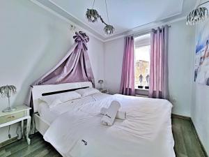 ein Schlafzimmer mit einem weißen Bett mit Hut darauf in der Unterkunft Campari in Toruń