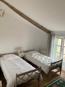 1 dormitorio con 2 camas y ventana en La Maison de Leontine, en La Livinière