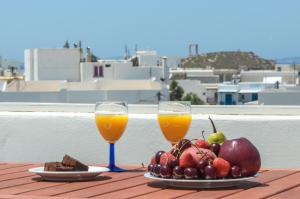 two glasses of orange juice and fruit on a table at Naxos Hotel Savvas in Naxos Chora