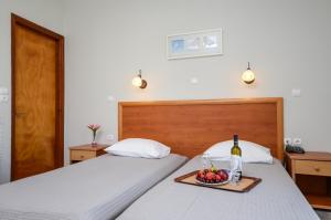 two beds with a tray of fruit and a bottle of wine at Naxos Hotel Savvas in Naxos Chora