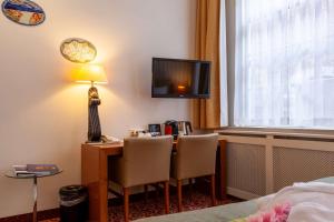 a hotel room with a desk with two chairs and a television at Best Western Museumhotels Delft in Delft