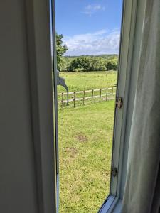 a window with a view of a field and a fence at Neigh's Gate in Cross Inn