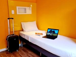 a room with a bed with a laptop and a suitcase at ibis budget Petropolis in Petrópolis