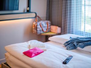 a bed with a pink bag and a remote control on it at Adagio Access Stuttgart Airport Messe in Leinfelden-Echterdingen