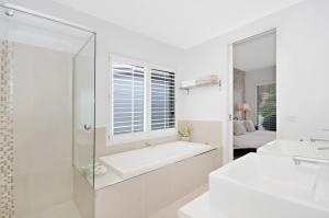 a white bathroom with a tub and a window at Central Warrnambool Townhouse in Warrnambool