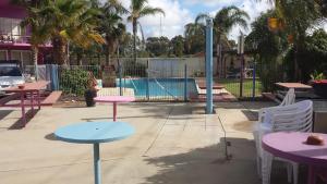 un patio con mesas y sillas frente a una piscina en Paddle Steamer Motel, en Swan Hill