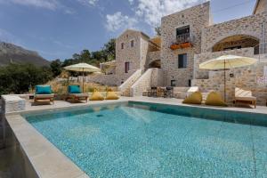 a pool with chairs and umbrellas next to a building at POSEIDON-APEA Villas in Limeni