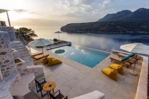 a pool with chairs and umbrellas next to a lake at POSEIDON-APEA Villas in Limeni