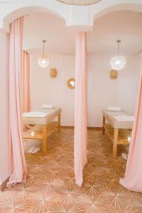 Le Pavillon de la Kasbah & SPA Marrakech في مراكش: غرفة مع ستائر وردية وطاولات على الأرض