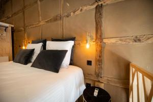 a bedroom with a bed with white sheets and black pillows at Paddock Lodge - Suites Wellness & Chambres d'hôtes in Stoumont