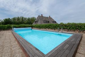 duży basen z domem w tle w obiekcie Heide Idyll w mieście Wenningstedt