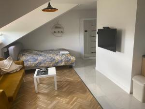 una pequeña sala de estar con cama y mesa. en Kawalerka premium B 30m2 - po remoncie - nowa!, en Varsovia