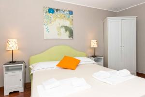 um quarto com uma cama branca e uma almofada laranja em San Salvario Apt with Balcony em Turim